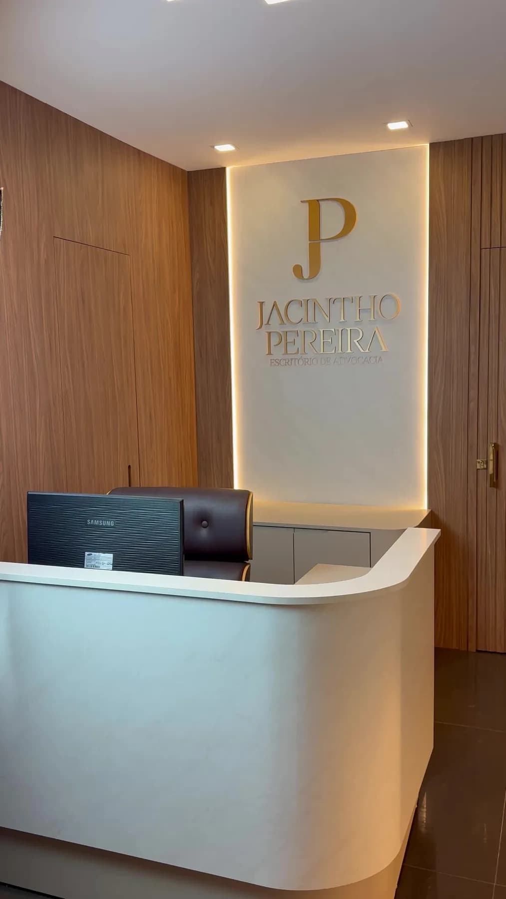 Recepção do escritório, com a marca em dourado retroiluminada